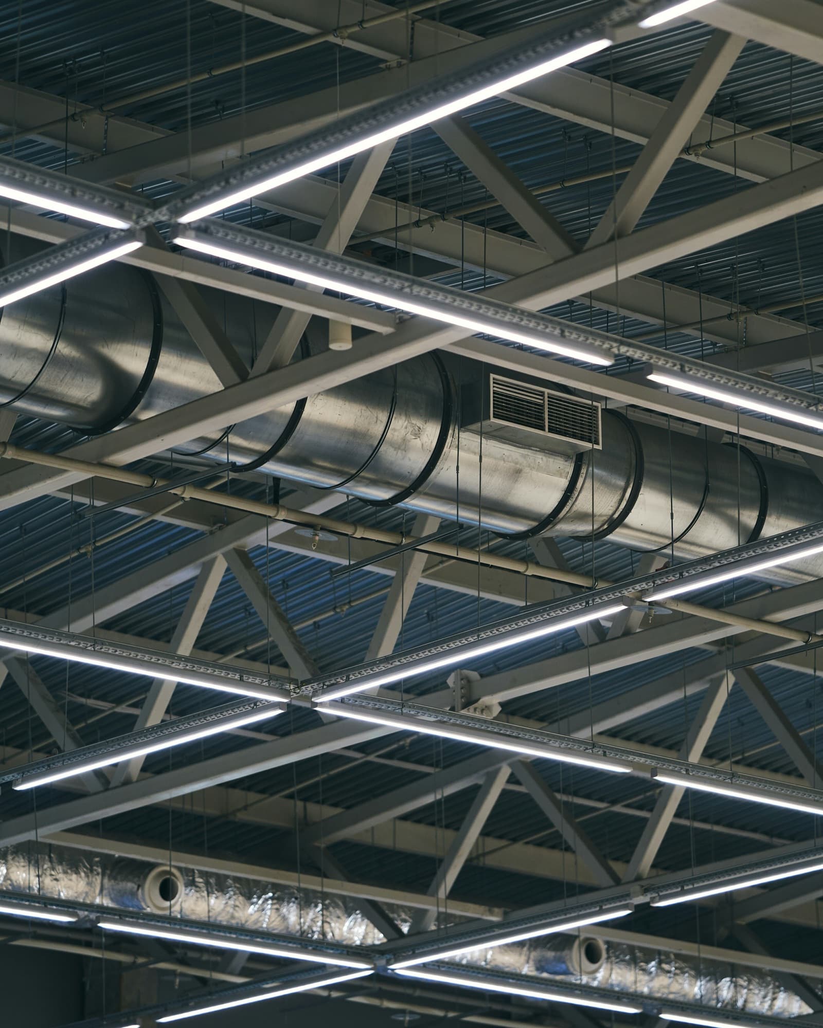 Spiral ductwork with a supply grille running under steel roof trusses